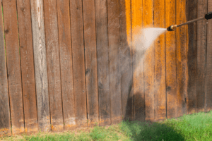 Person power washing wooden fence.